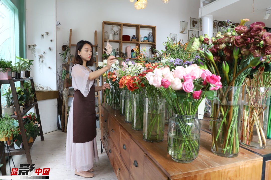 王黎媛是一名河南姑娘，在昆明念完大學(xué)后，就再也舍不下春城的藍(lán)天陽(yáng)光、青山碧水，更舍不下這里的四時(shí)繁花，于是就干脆留了下來(lái)，成了一名媒體人。2017年的時(shí)候又毅然辭去工作，創(chuàng)業(yè)開(kāi)起了花店，成了都市里的一名“花房姑娘”。圖為王黎媛在自己的花店中整理鮮花。新華網(wǎng) 周亞平/攝 念新洪/文
